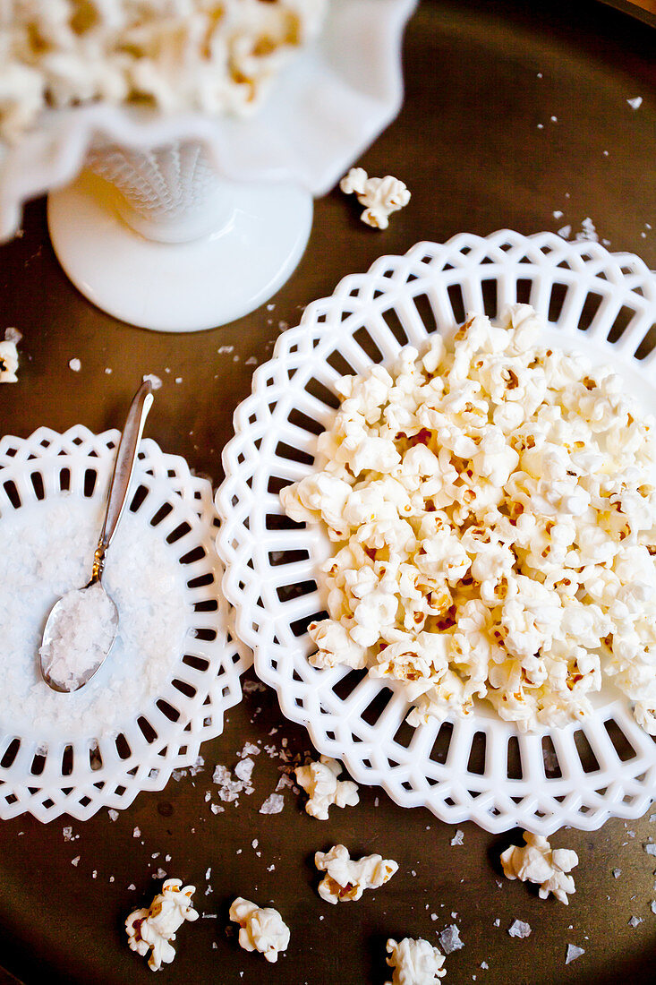 Antique white plates and dishes with popcorn and sea salt on a gold tables