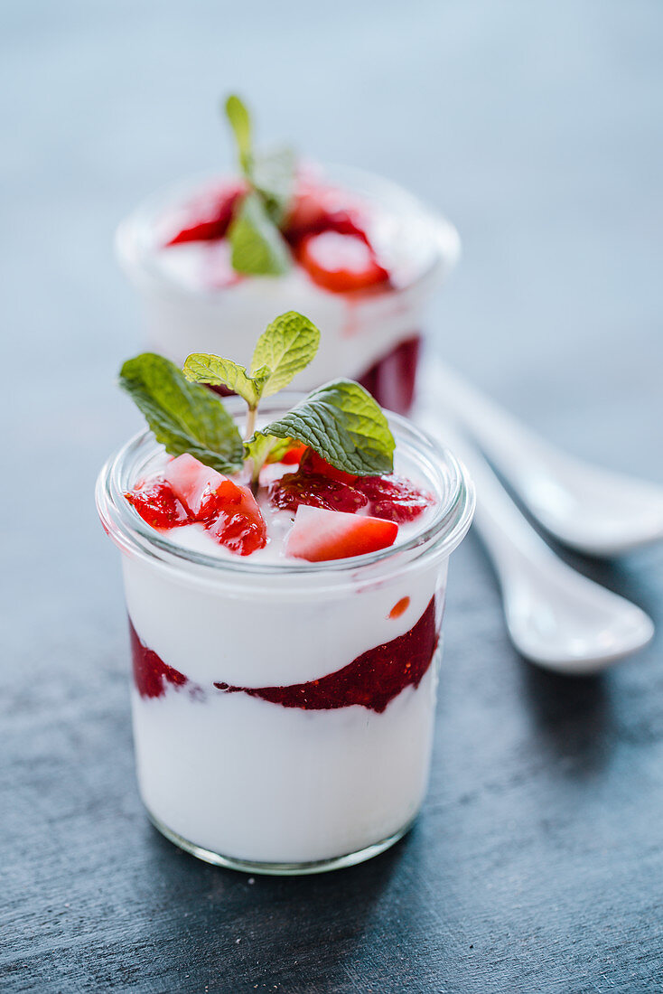 Yoghurt dessert with strawberry jam, fresh strawberries and mint
