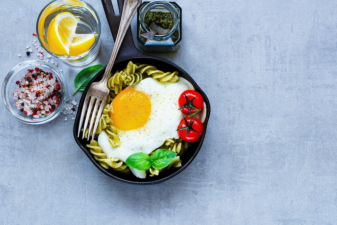 Nudelpfanne mit Pesto, Spiegelei, gebratenen Tomaten und Basilikum