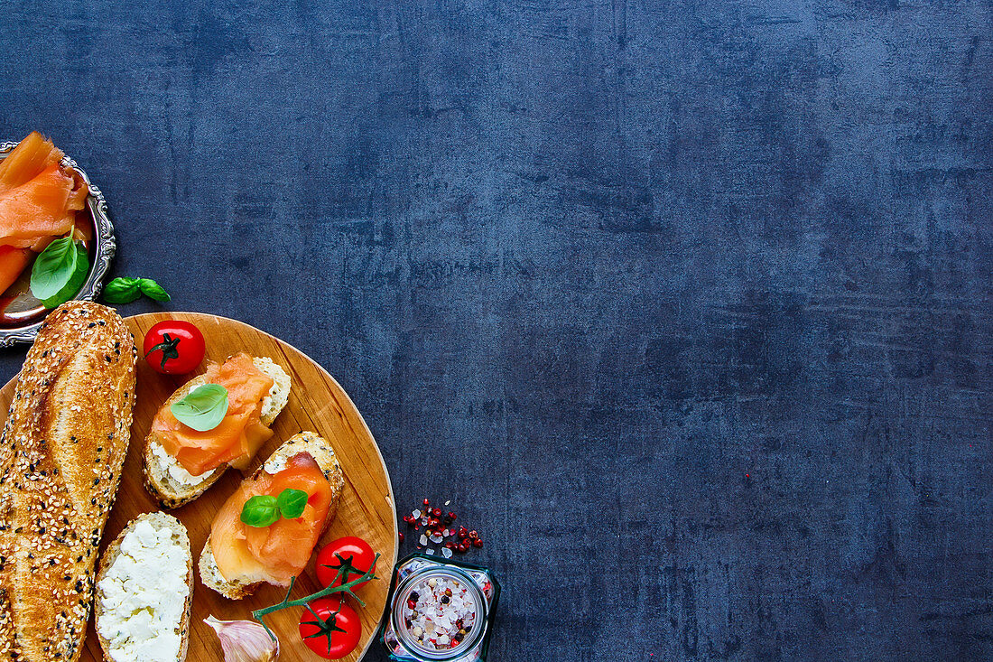 Close up of sandwiches with smoked salmon, creamcheese, basil and healthy ingredients on round wooden board