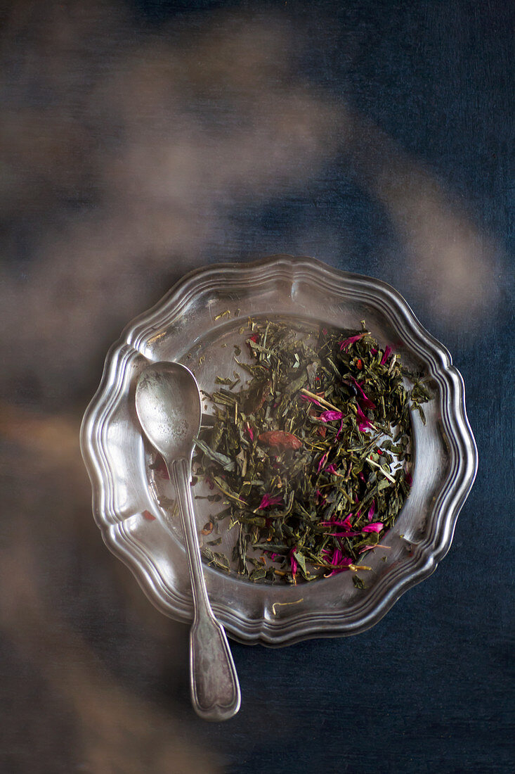 Tea leaves on a metal dish with a spoon