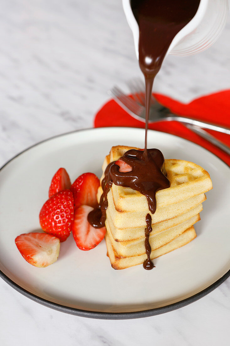 Valentine waffles with strawberries and chocolate sauce
