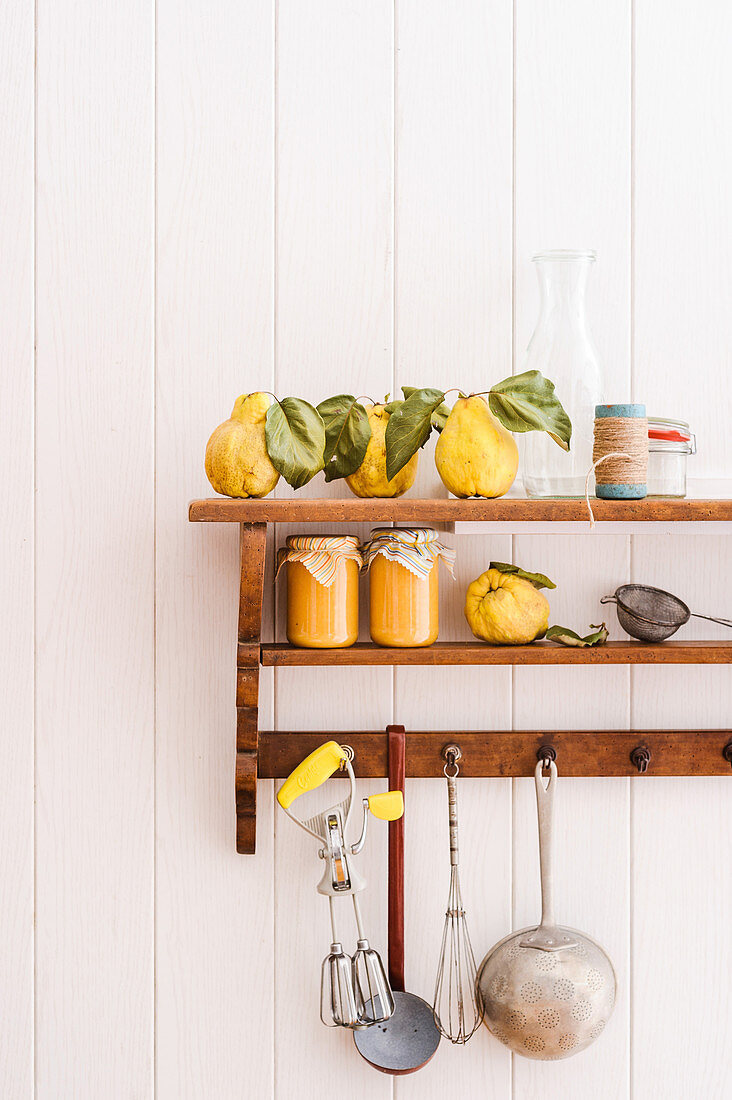 Quince purée, fresh quinces and kitchen utensils on a wall shelf