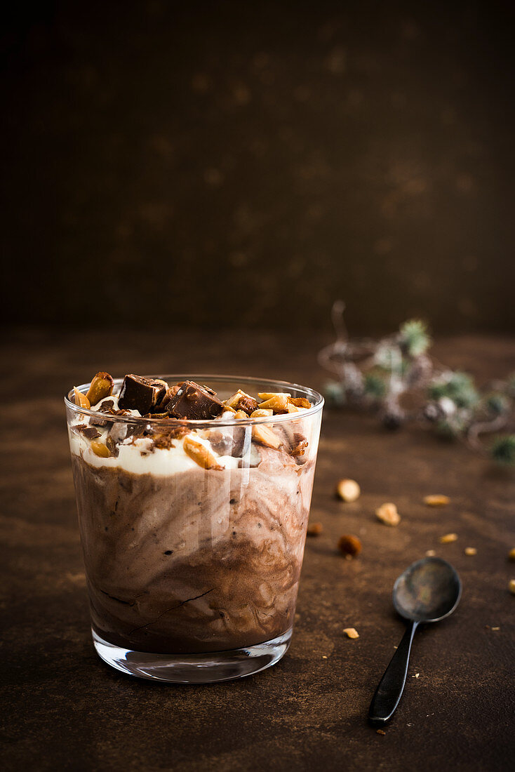 Chocolate pudding with roasted nuts and cream in a glass