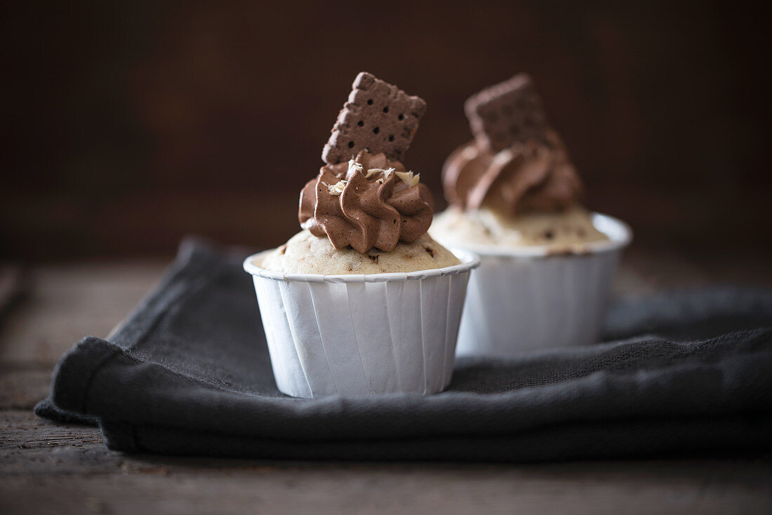 Vegan stracciatella muffins with a chocolate cream topping decorated with biscuits