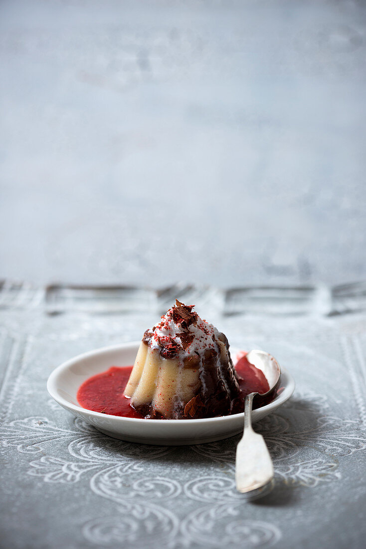 Vegan chocolate and vanilla pudding with strawberry sauce topped with whipped soya cream, strawberry powder and grated chocolate