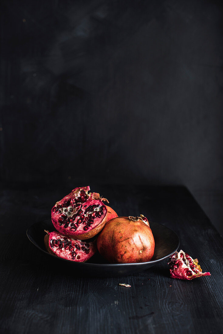 Granatapfel, ganz und aufgeschnitten, in einer Schale