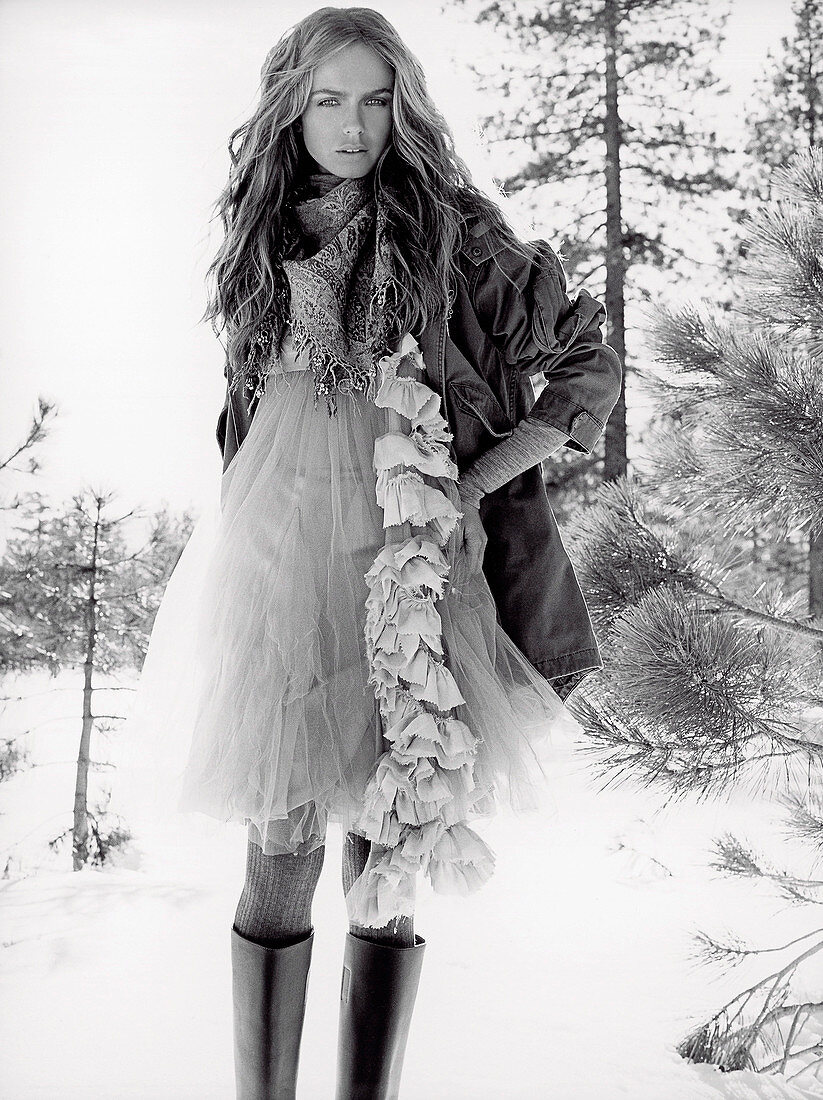 A young woman in the snow wearing a tutu dress and a parka (black-and-white shot)
