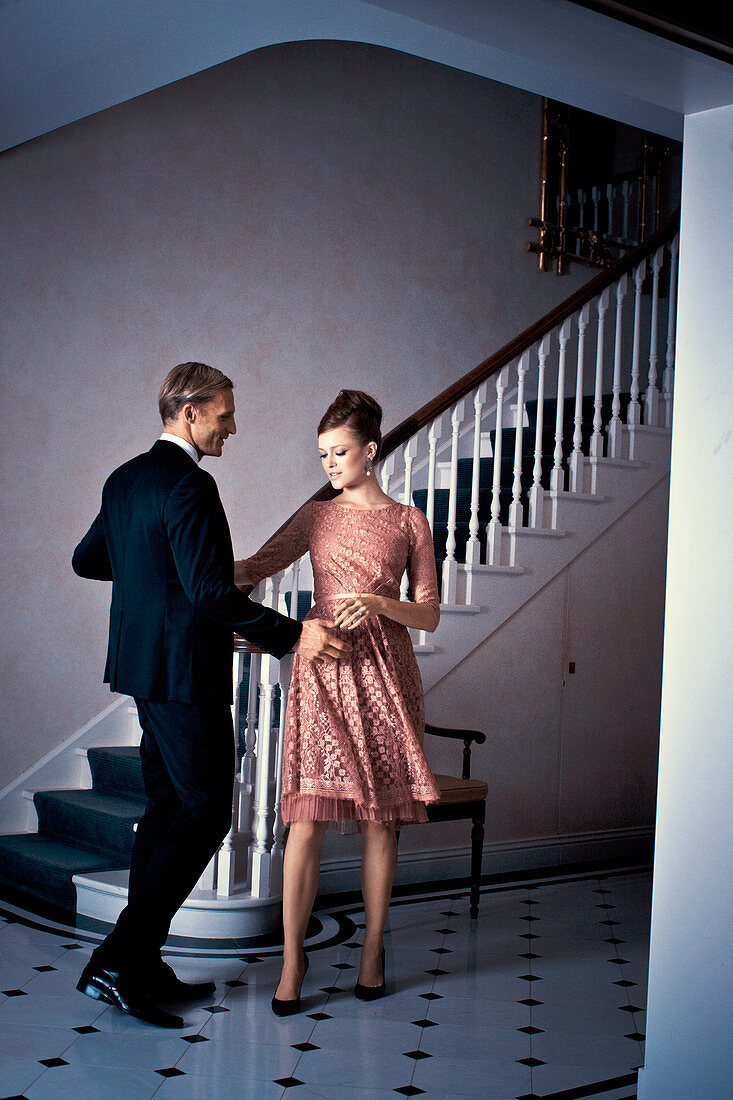 An elegantly dressed couple dancing in a hallway