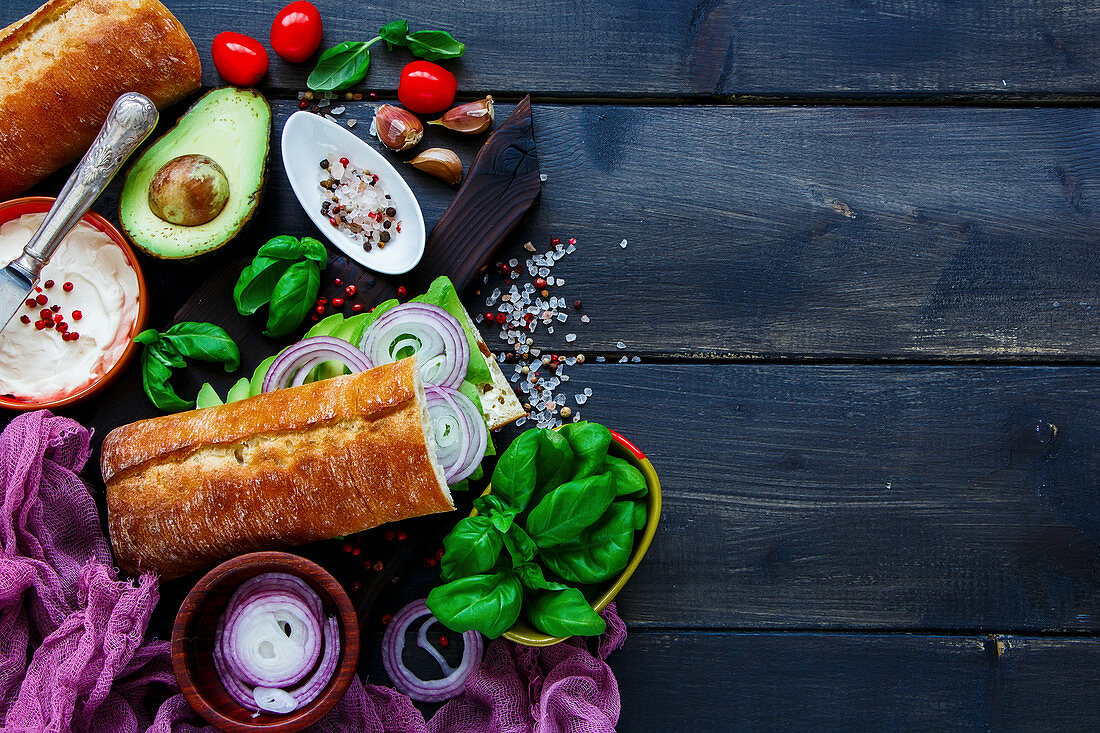 Delicious Vegetarian Sandwich (with Avocado, Tomato, Onion, Cream Cheese, Herbs and Spices) on dark rustic background