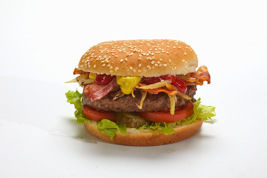 A hamburger with bacon and cheese against a white surface