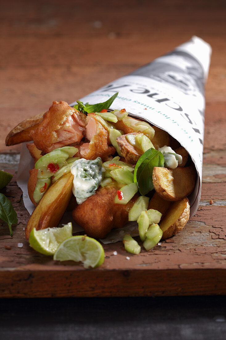 Fish and chips with cucumber and remoulade wrapped in newspaper