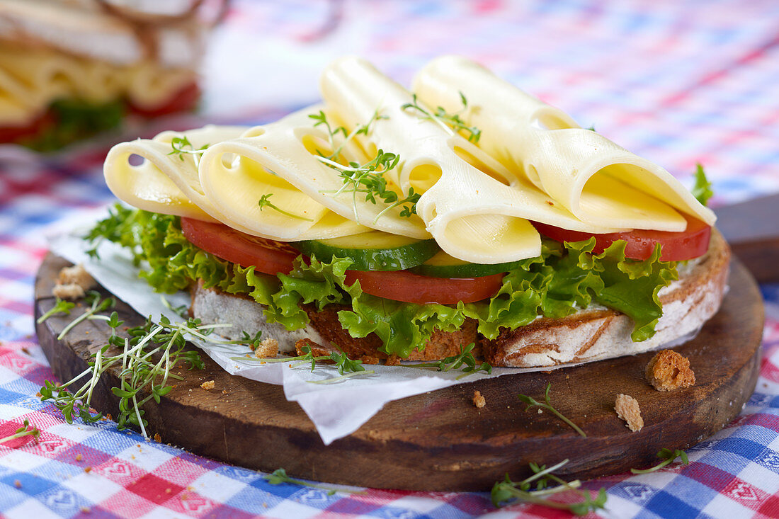 A slice of crusty bread topped with gouda, cucumber, tomatoes and lettuce