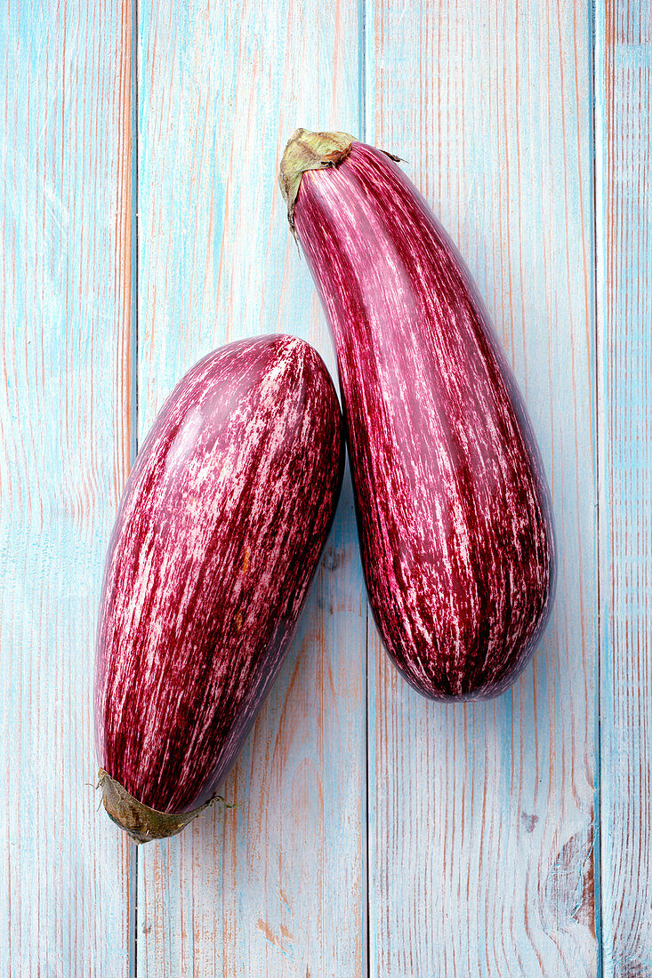 Two aubergines on a wooden surface