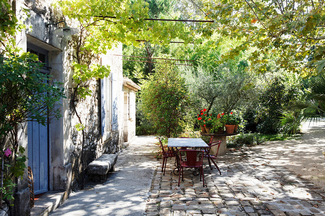 Tisch mit Vintage Stühlen auf Terrassenplatz vor provenzalischem Haus