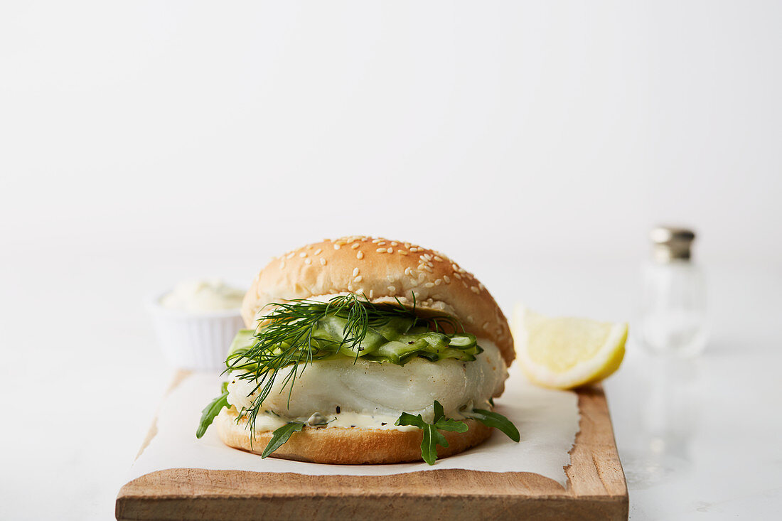 Fischburger mit Gurken und Dill auf Holzschneidebrett