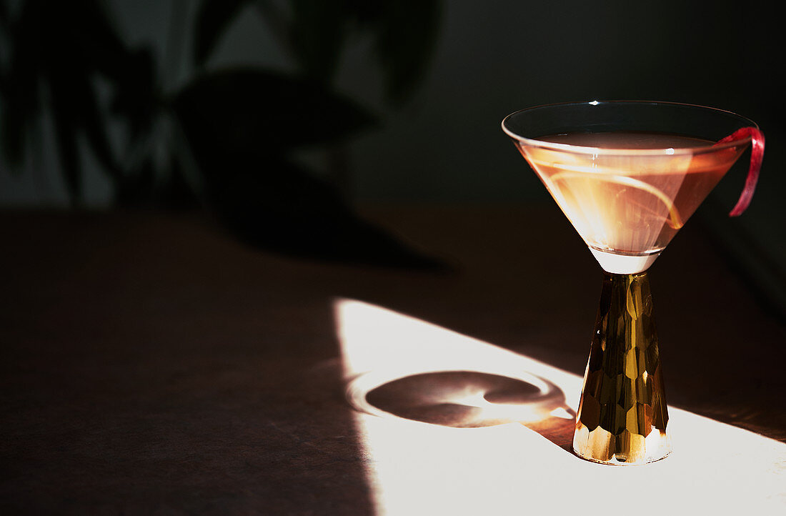 A summer cocktail in a stemmed glass casting a shadow