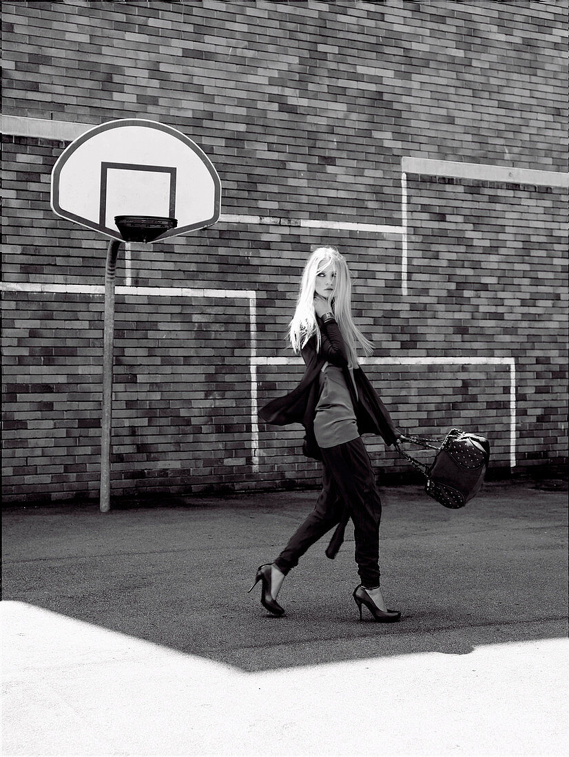 A young woman on a basketball court wearing a dark, sporty outfit (black-and-white shot)