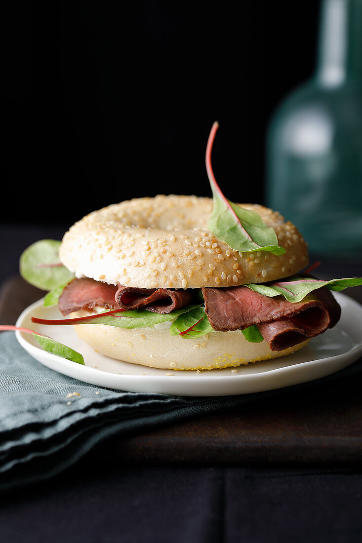 A sesame seed bagel with roast beef and salad