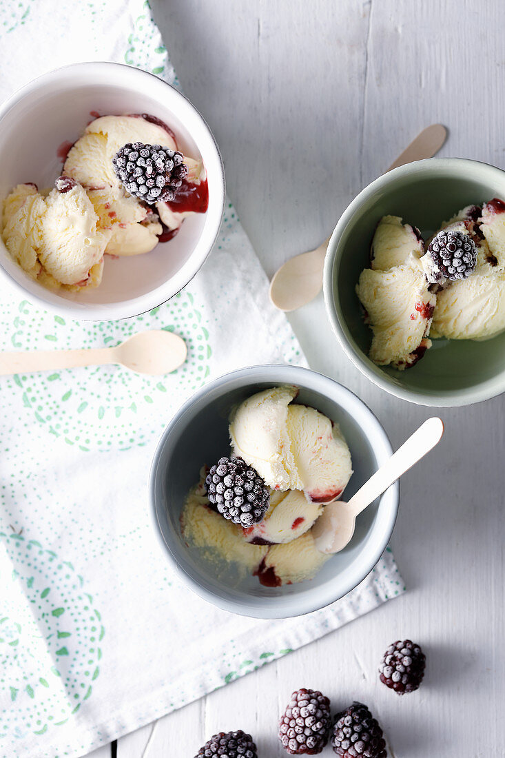 Three cups of vanilla and blackberry ice cream with frozen blackberries