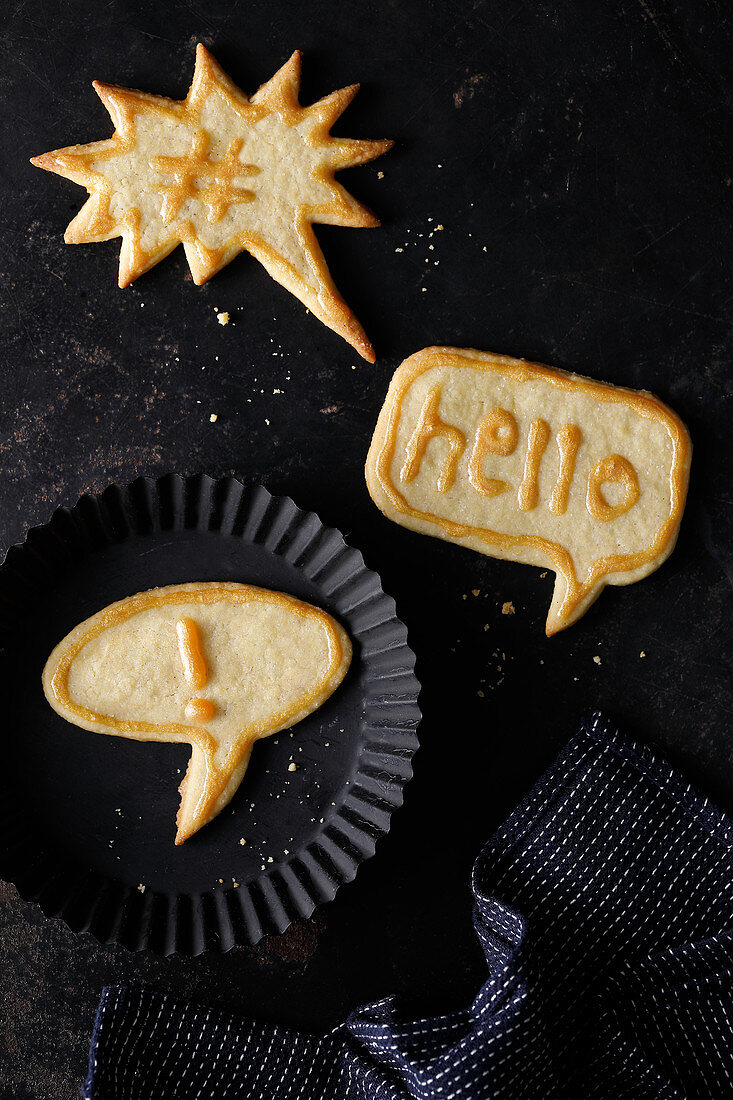 Three comic-style speech bubble biscuits with golden sugar writing