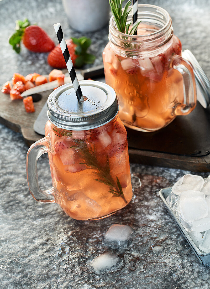 Zwei Gläser Erdbeer-Rosmarin-Switchel mit Eiswürfeln