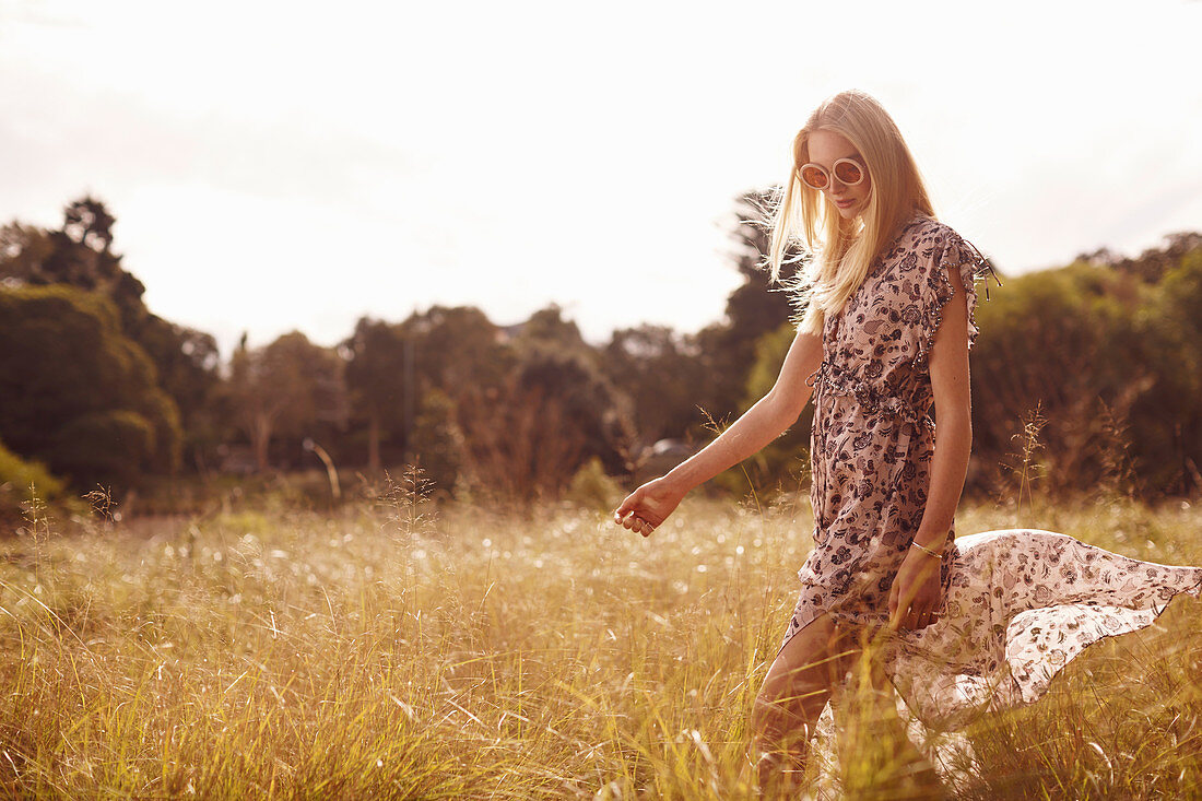 A young blonde woman wearing a summer dress outside in a field