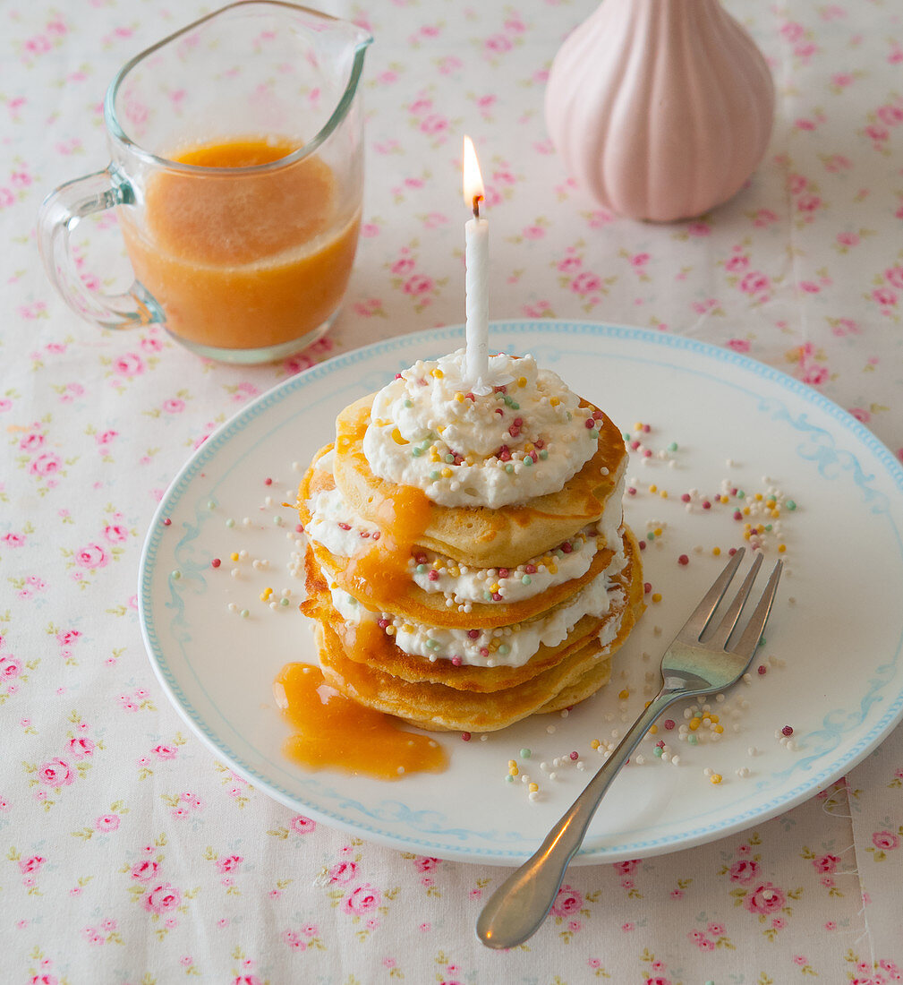 A birthday pancake-cake with caramel sauce and colourful sugar pearls