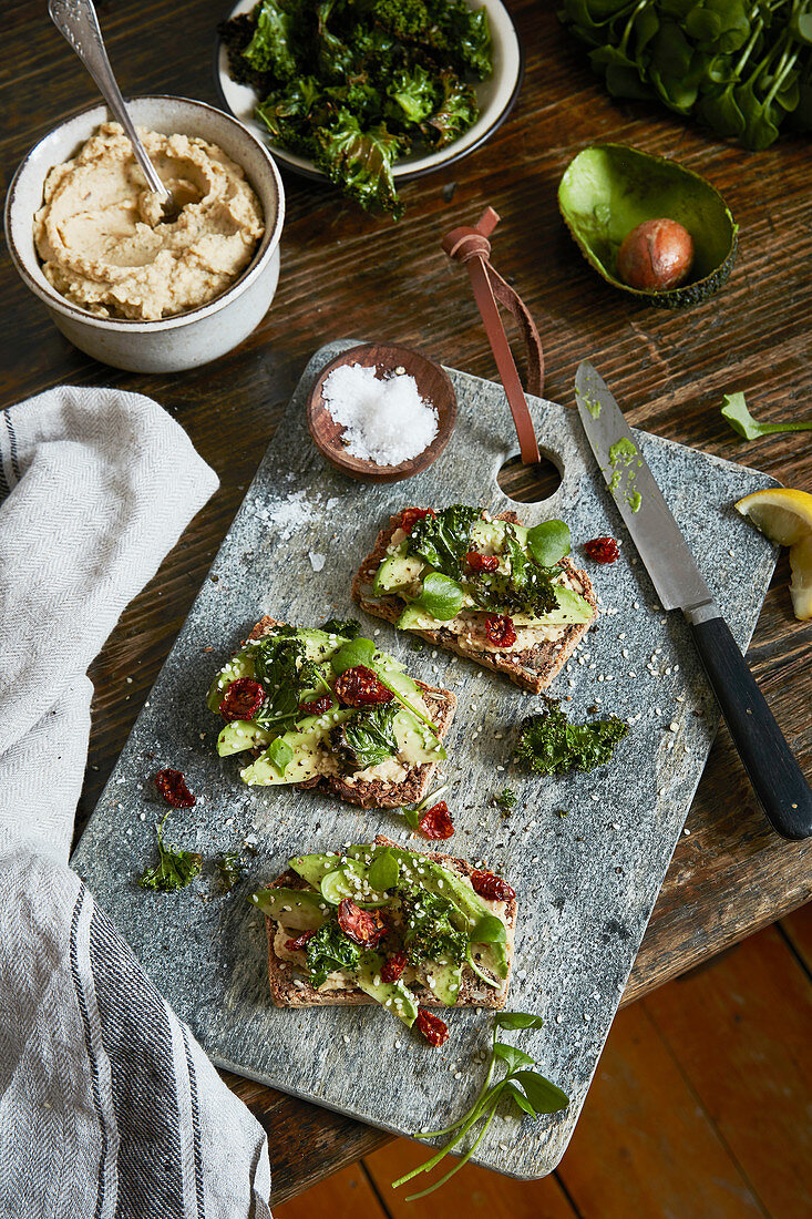 Buckwheet bread with avocado and dried tomtato on a choppingboard.