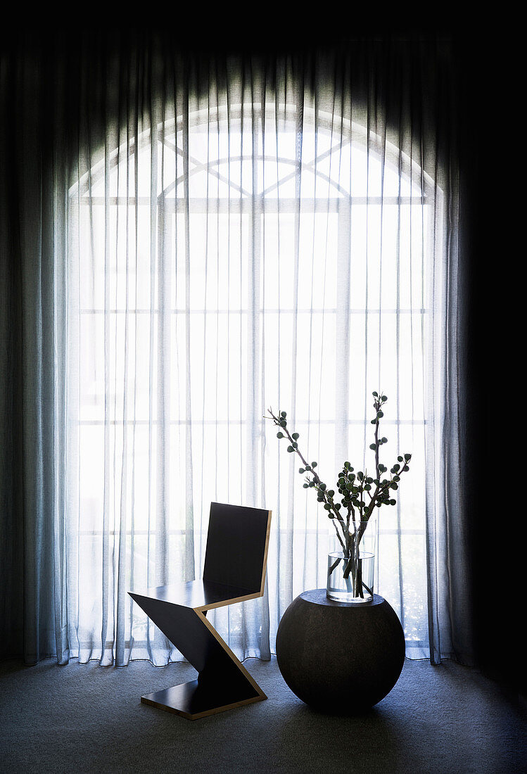 Zig-Zag Stuhl und Beistelltisch mit Glasvase vor Rundbogenfenster mit Vorhang