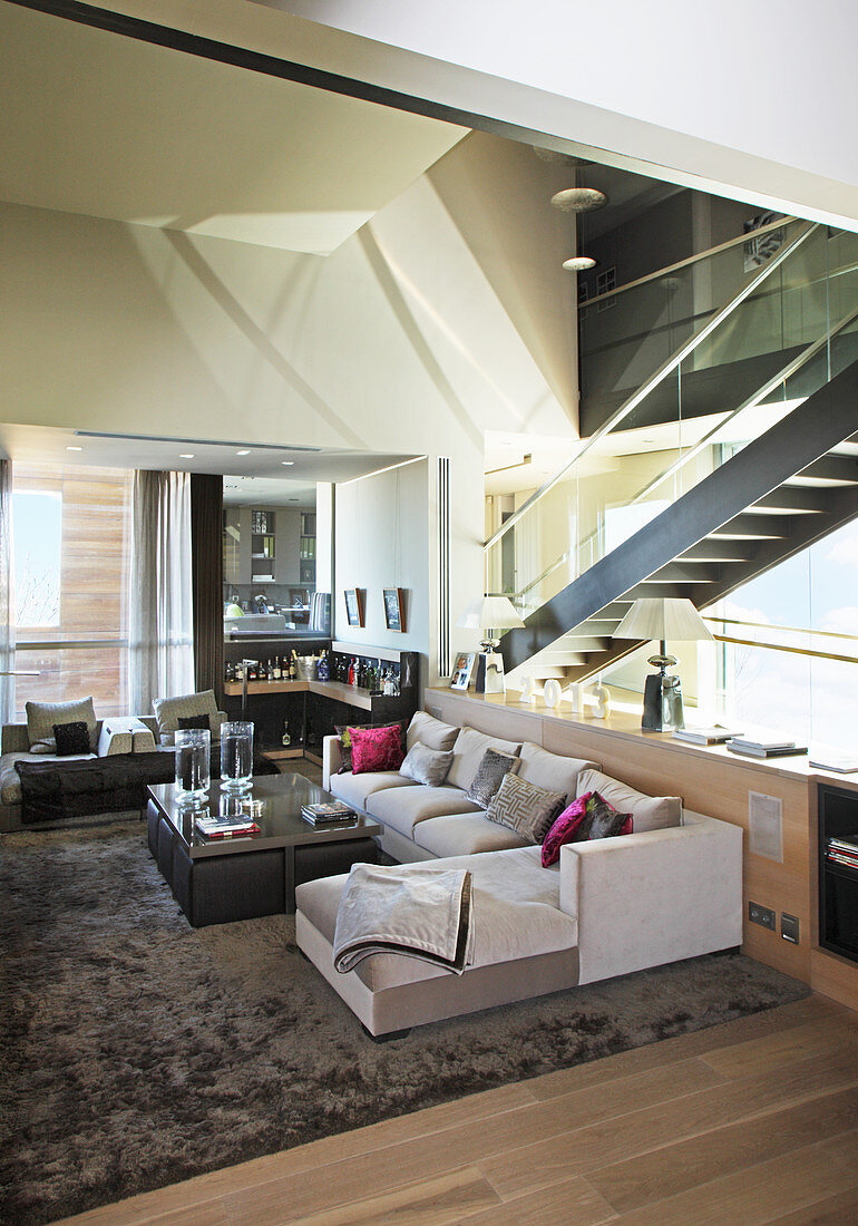 Modernes Wohnzimmer mit Treppe hinter der Glaswand