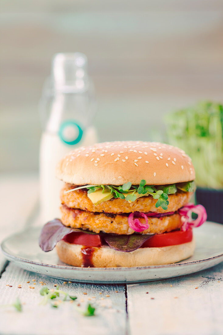 A double burger with tofu, avocado and a bottle of cereal milk