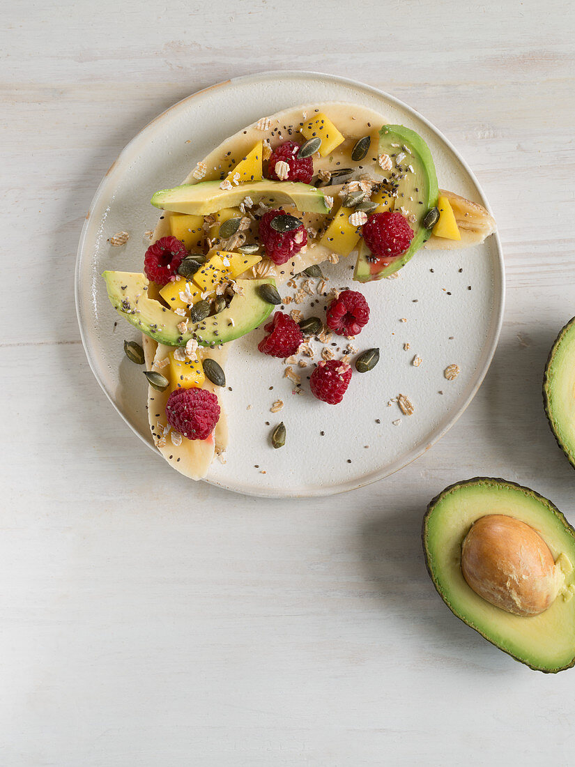 Halved bananas with avocado, mango, raspberries and chia