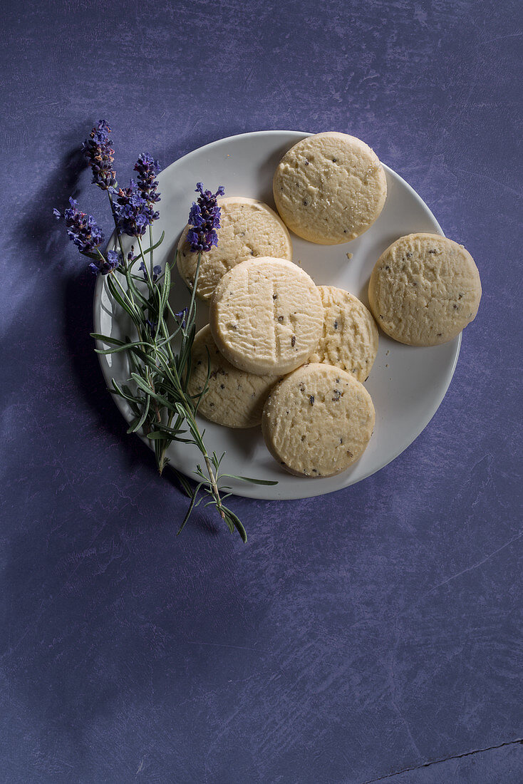 Sables mit Lavendel auf Teller vor violettem Hintergrund (Aufsicht)