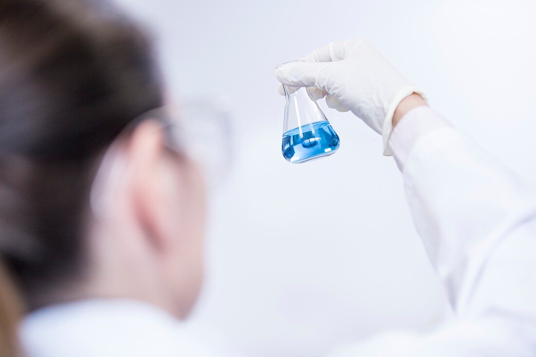 Lab assistant looking at flask