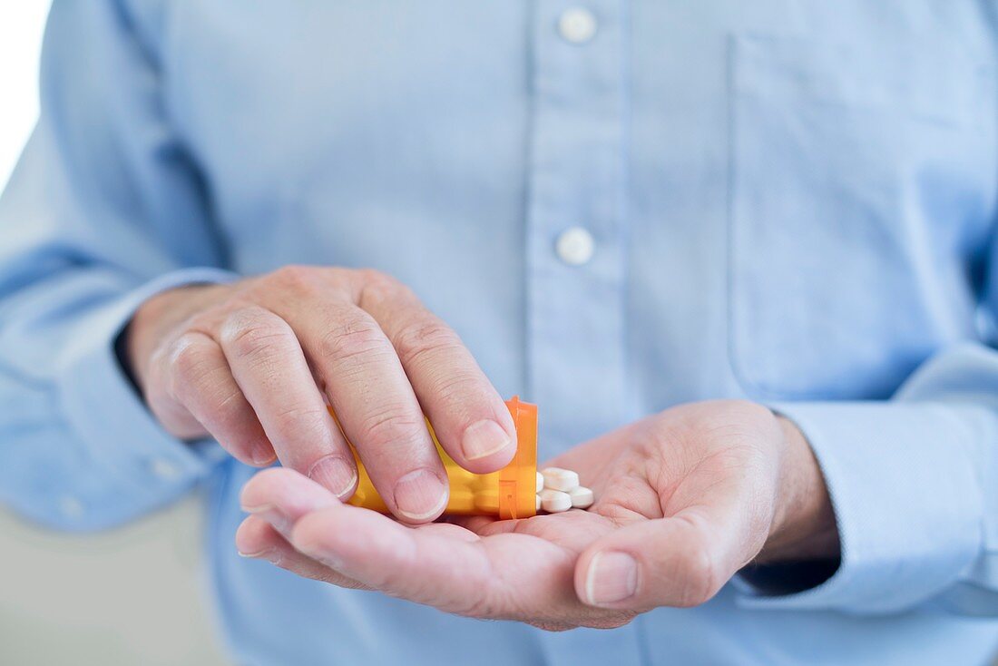 Man pouring pills onto hand from bottle