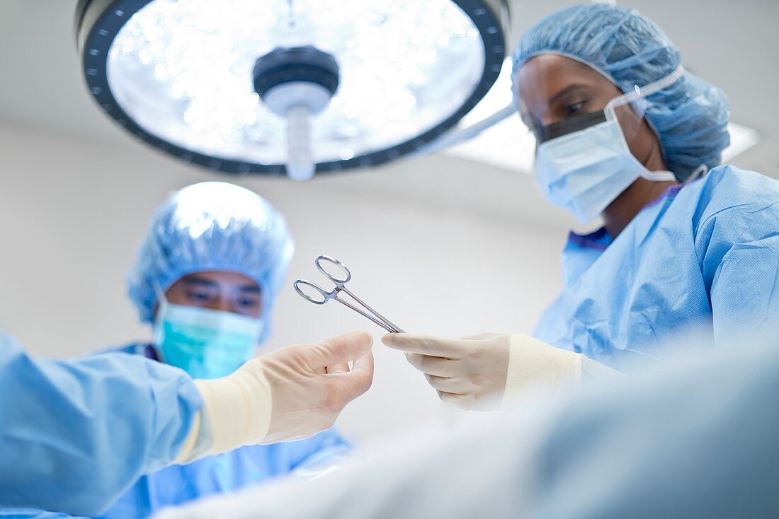 Nurse passing surgical scissors to surgeon