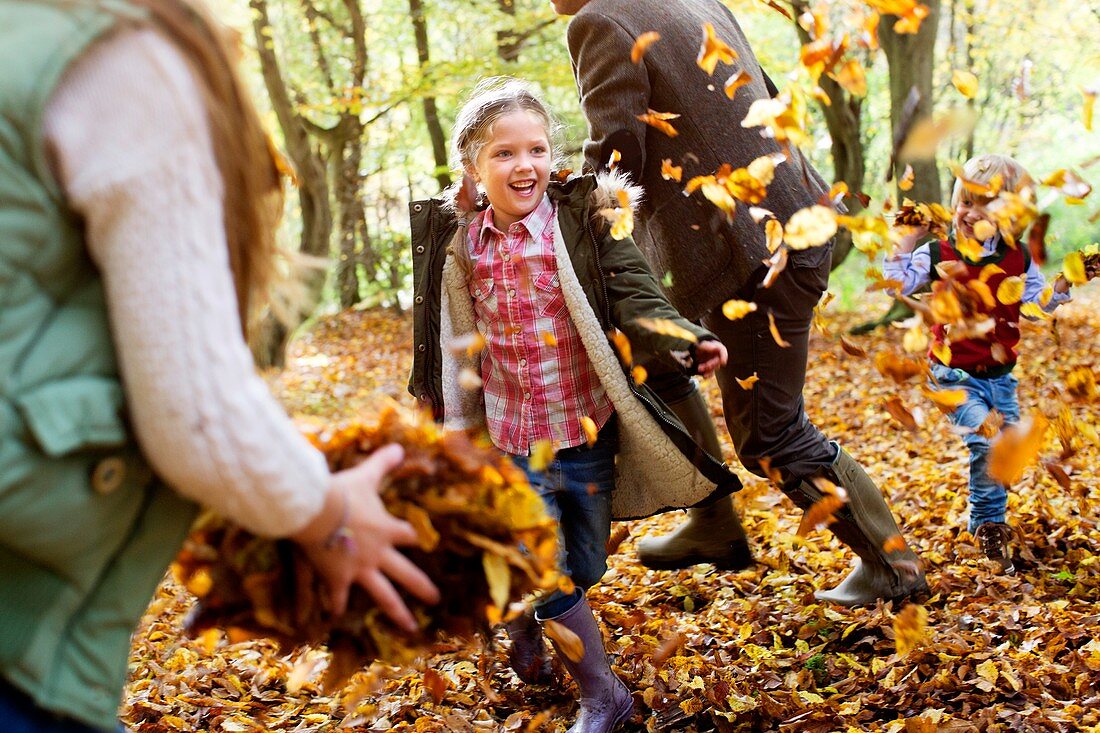 Family playing in Autumn leaves