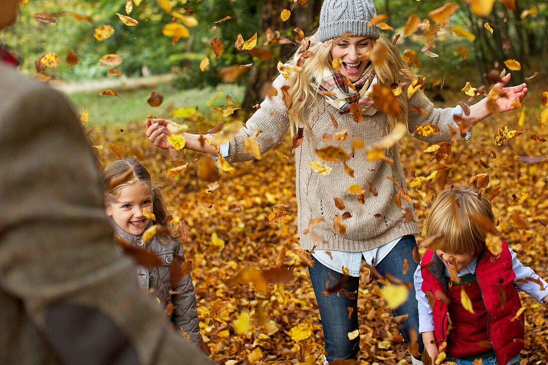 Family playing in Autumn leaves