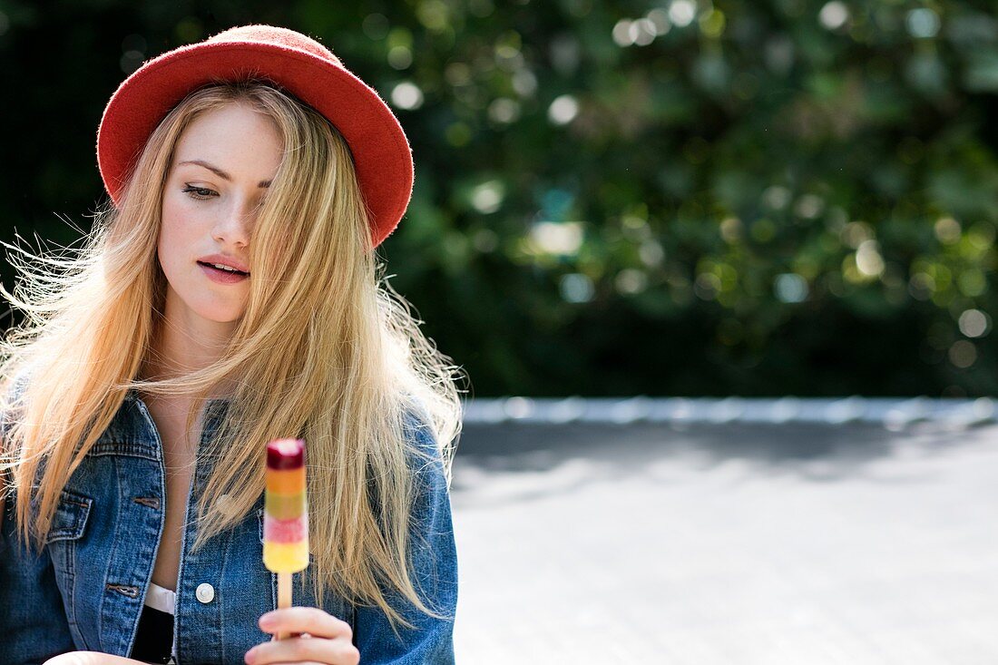 Woman in red hat eating ice lolly