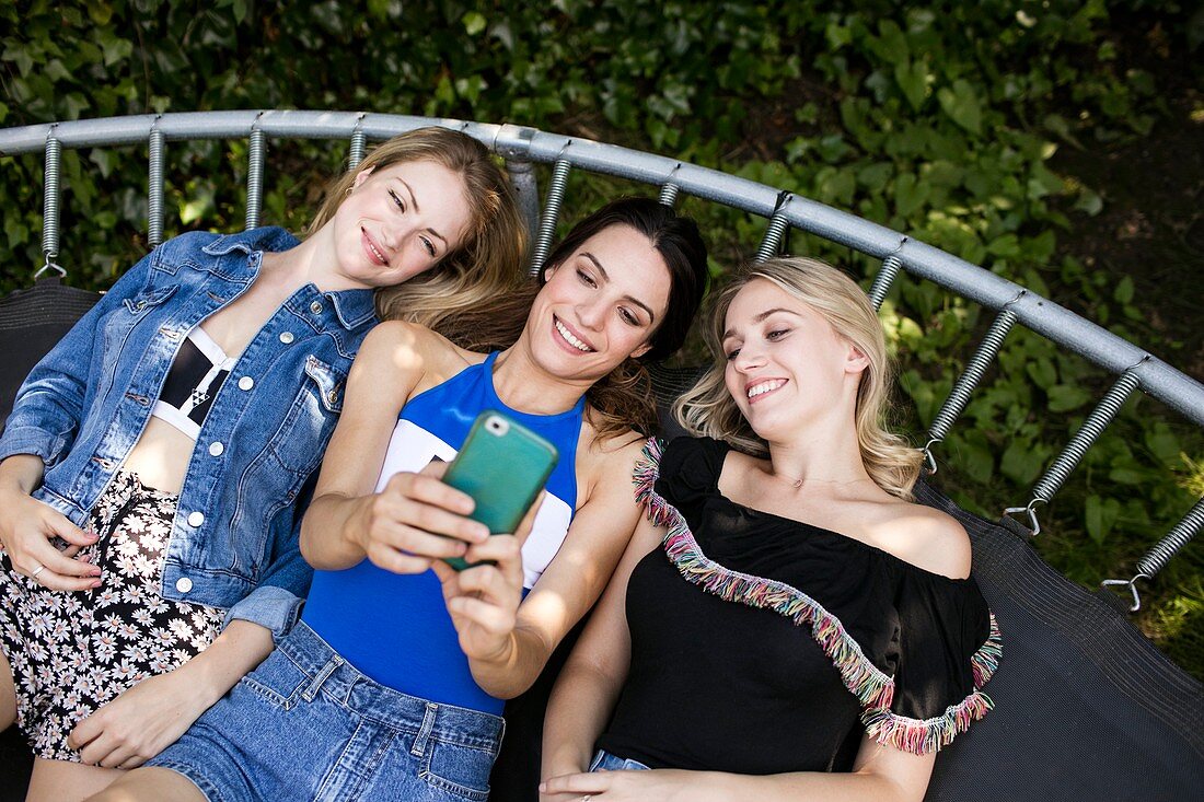 Three young women lying on trampoline