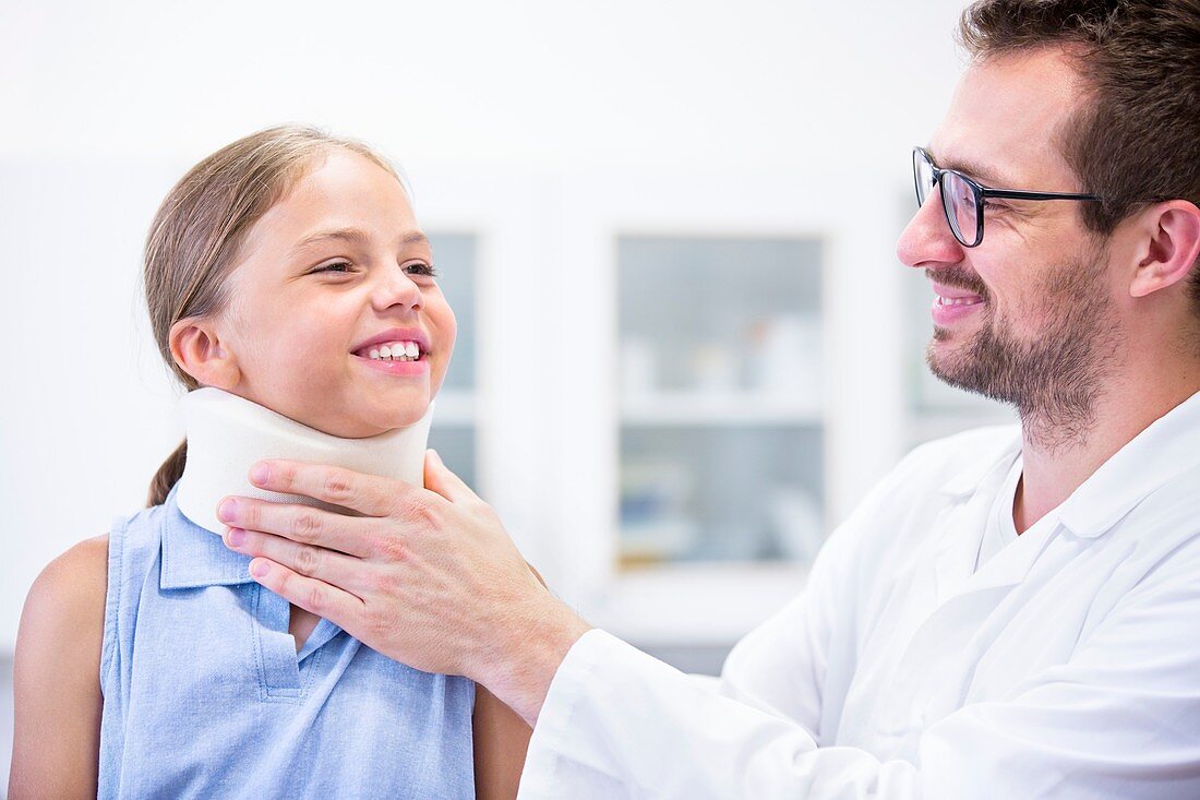 Doctor applying neck support to girl