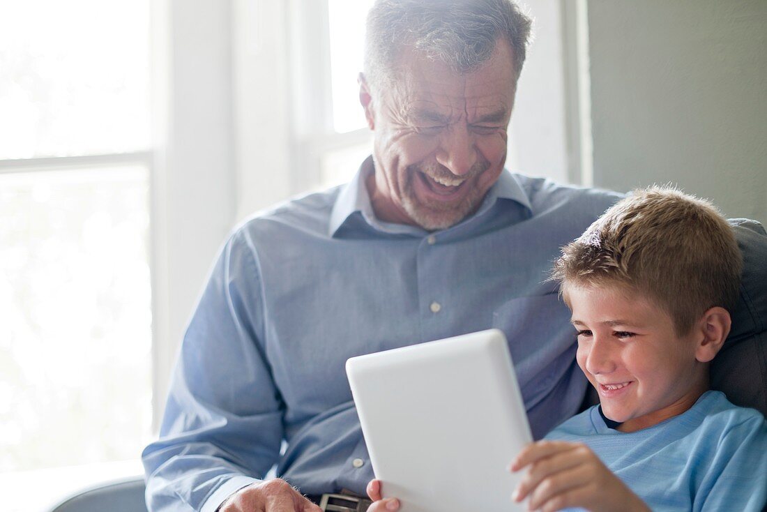 Boy using tablet with his grandfather