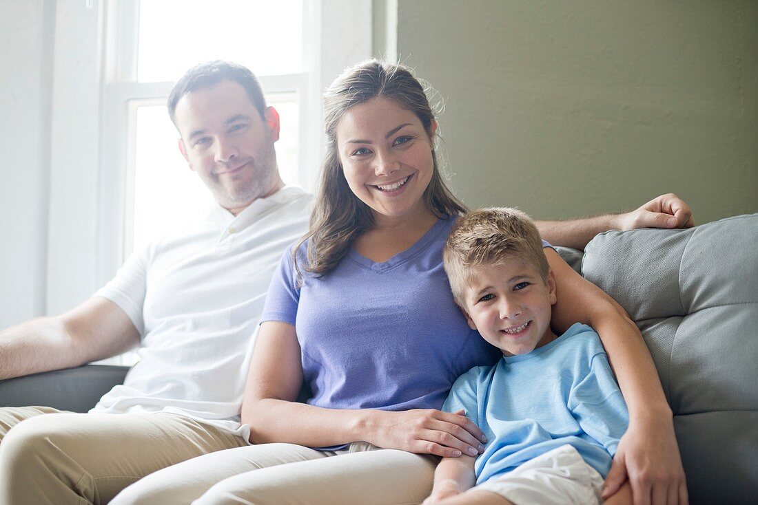 Boy sitting on sofa with his mother and father, portrait