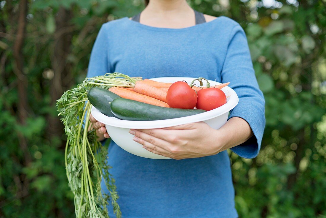 Woman holding bowl with fresh vegetables