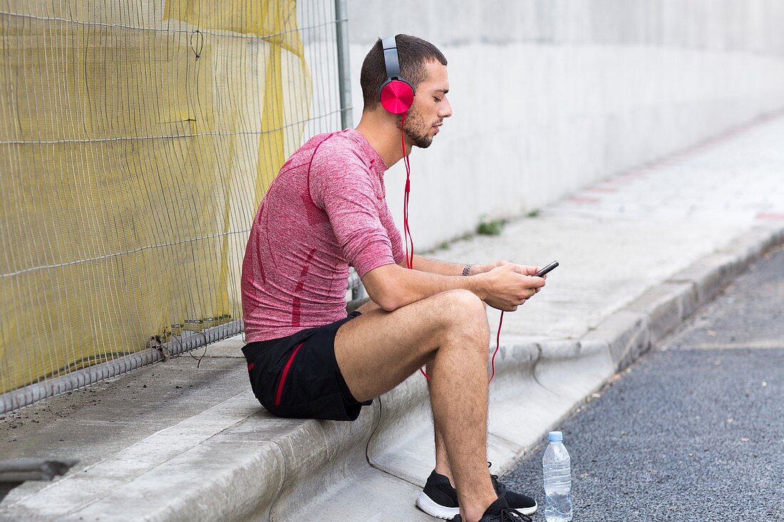 Young man wearing headphones on smartphone