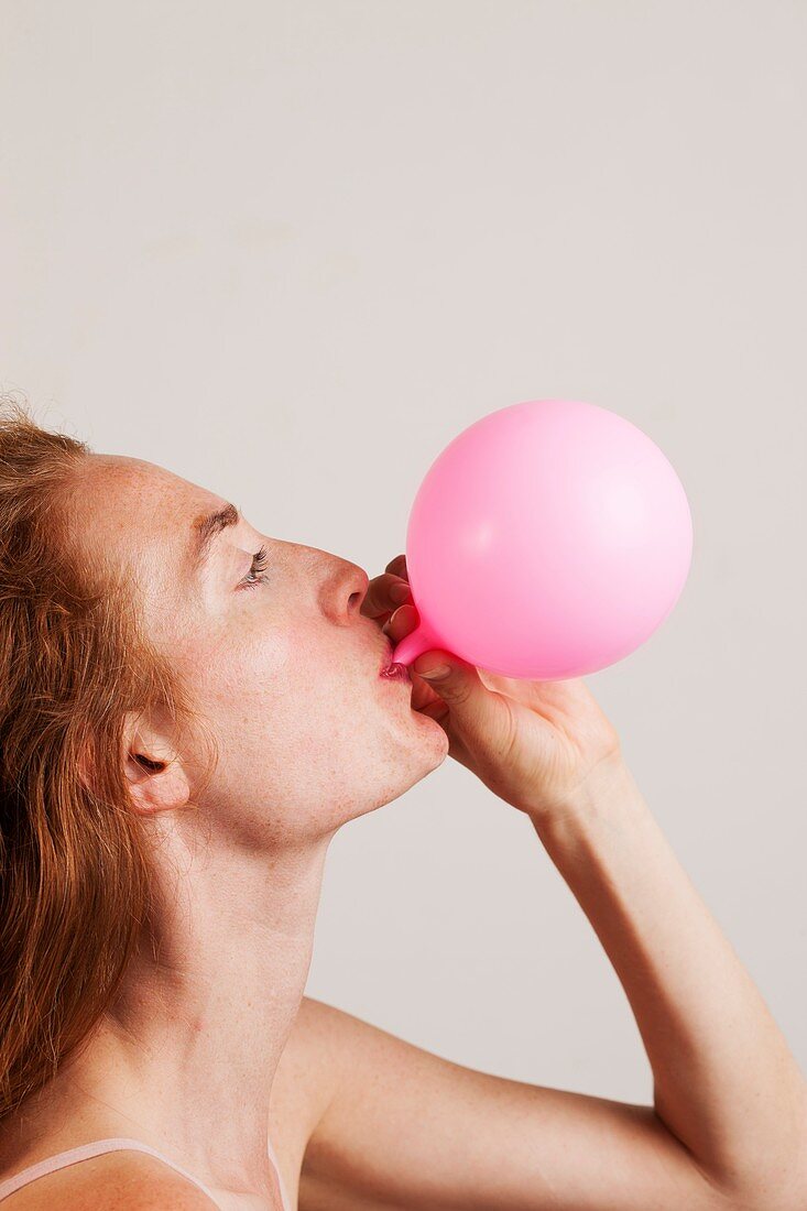 Woman blowing up pink balloon