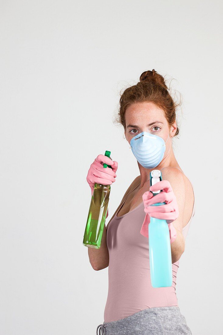 Woman wearing face mask holding cleaning materials