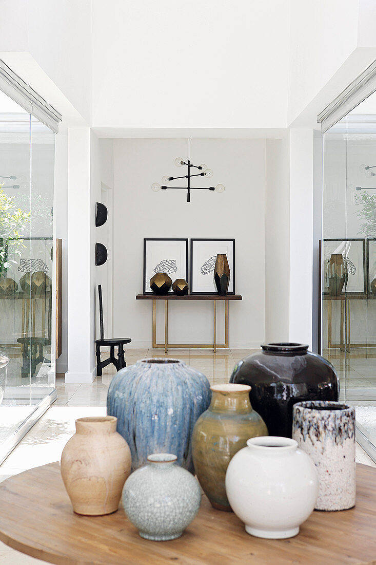 Ceramic vases on table in front of artworks on console table in foyer