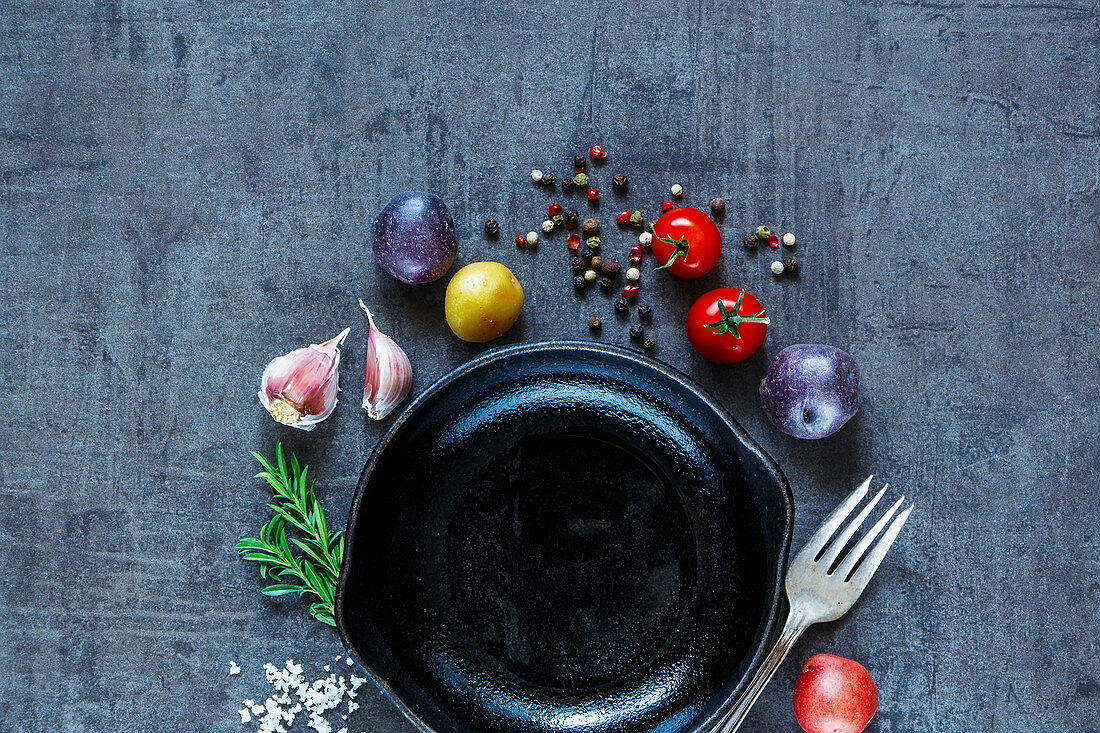 Raw vegetables background with various organic ingredients (potatoes, tomatoes, garlic and spices) over dark grunge table